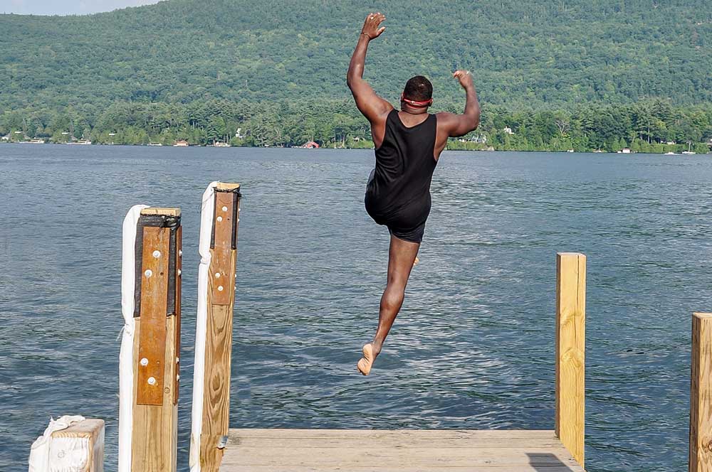 Man jumping into the lake off a dock
