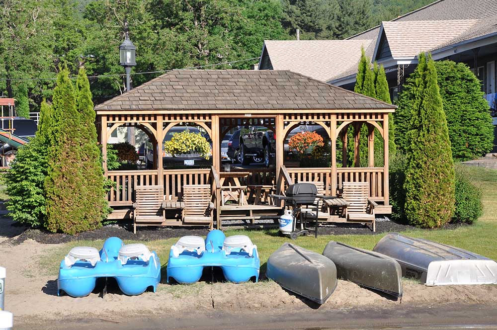 Canoes and boats on the shore of the lake in front of a gazebo