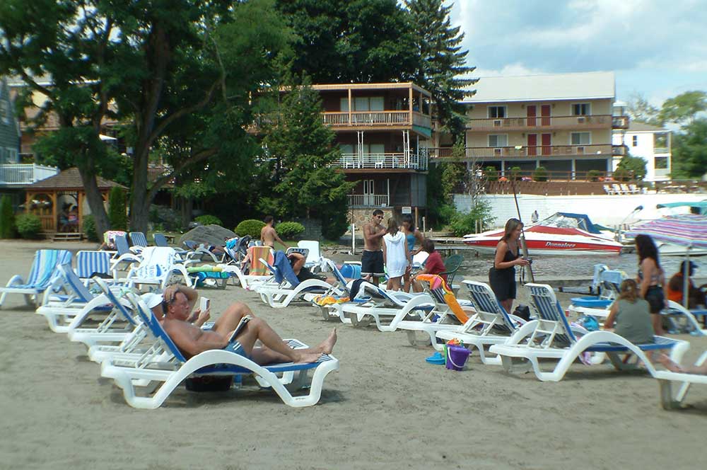 Beach with people relaxing in chaise lounge chairs