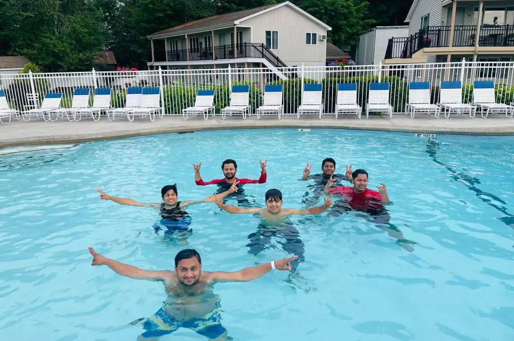 Family making peace sign while swimming in a pool.